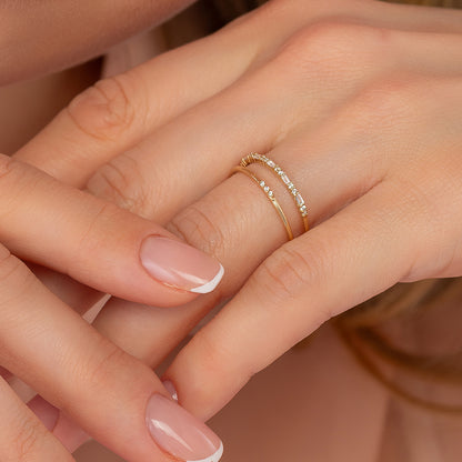 A close-up of a person's hands wearing a gold ring with a diamond accent.