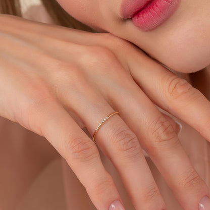 A close-up of a person's hand wearing a delicate gold ring with a small diamond accent.