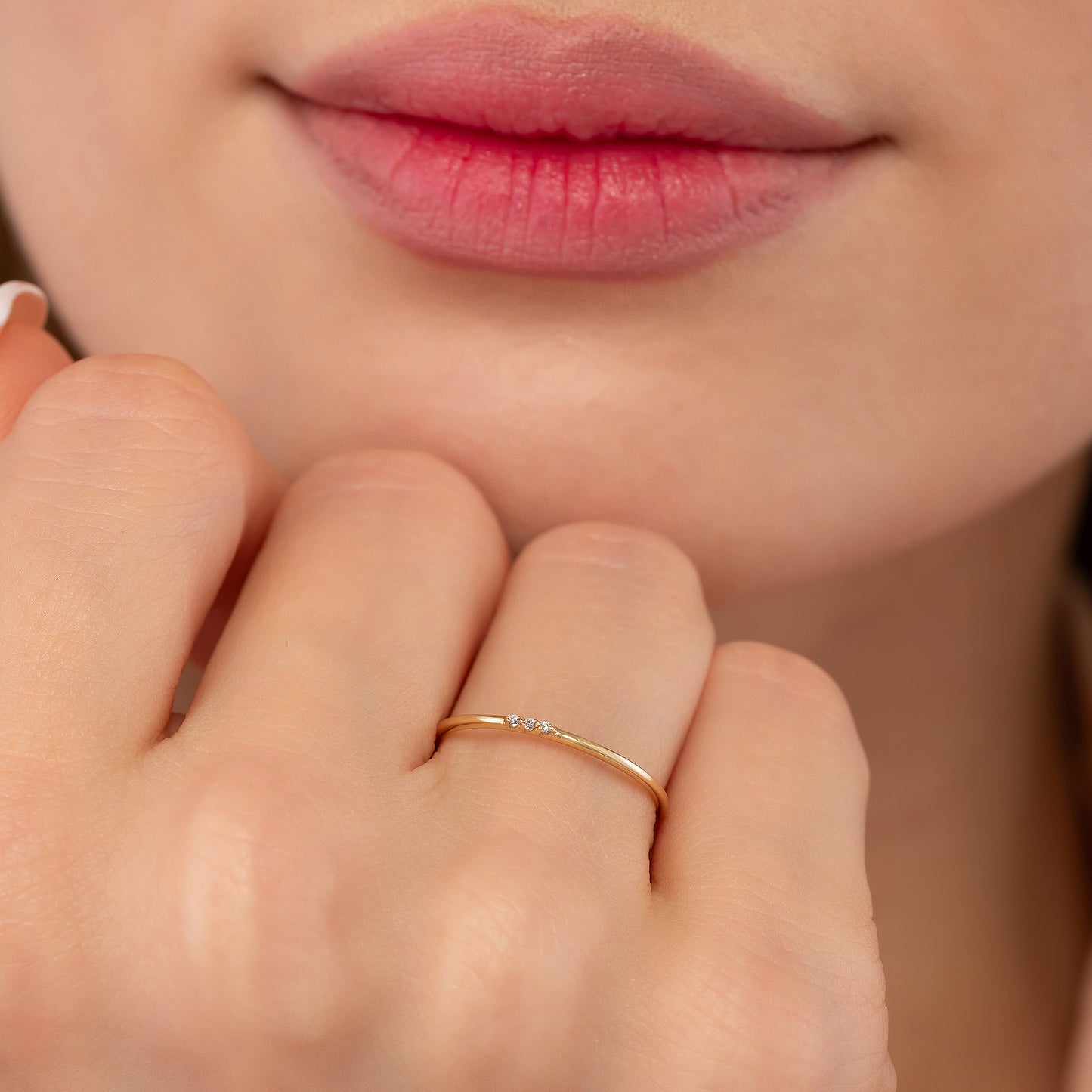 A close-up of a person's hand wearing a gold ring with a small diamond.
