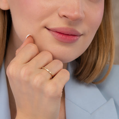 A close-up of a woman's face, focusing on her hand and finger adorned with a ring.