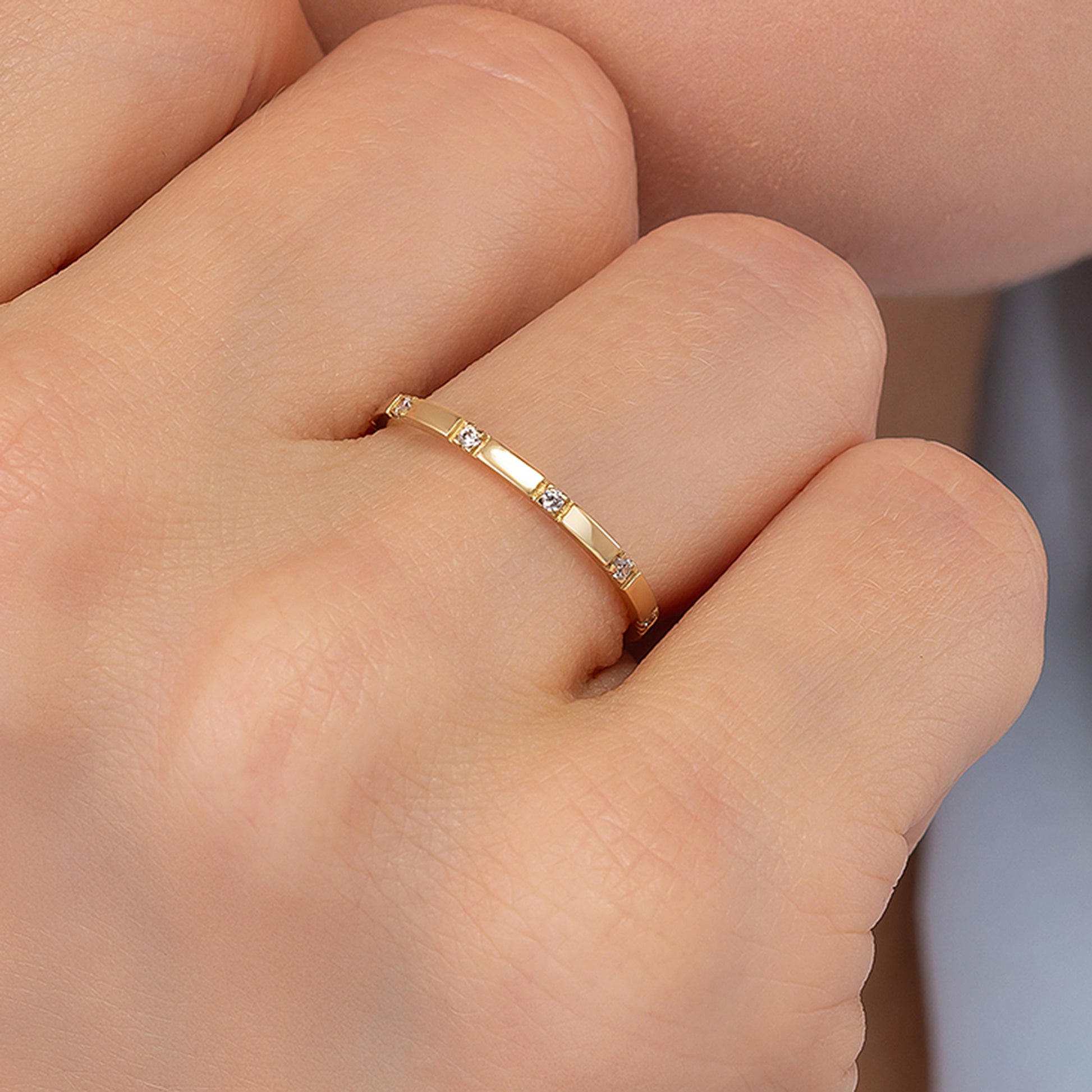 A close-up view of a person's hand wearing a gold ring with small diamonds.