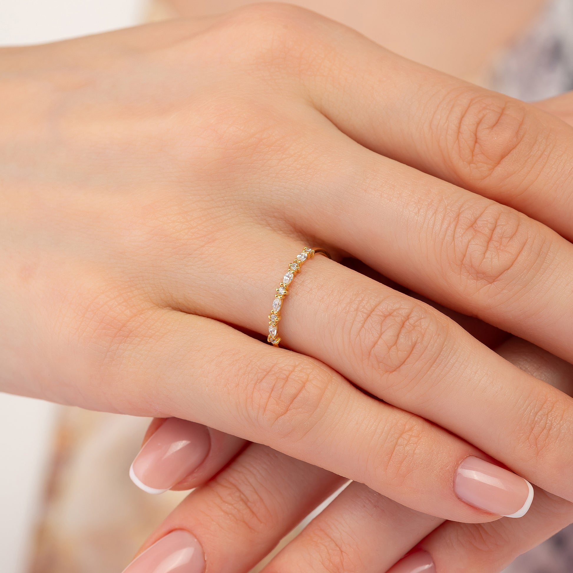 A close-up image of a person's hand wearing a gold ring with a row of small diamonds.