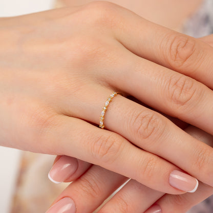 A close-up image of a person's hand wearing a gold ring with a row of small diamonds.