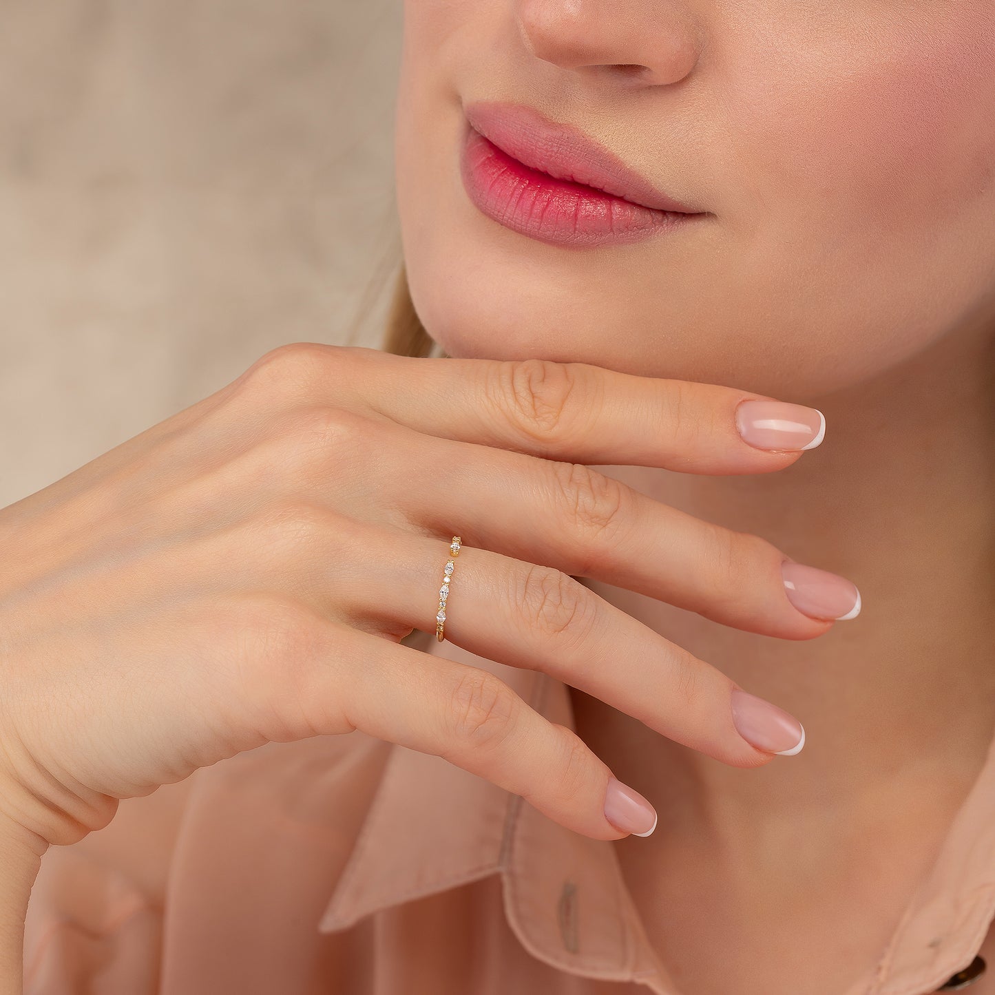 A close-up of a woman's hand wearing a ring, with her chin resting on her hand.