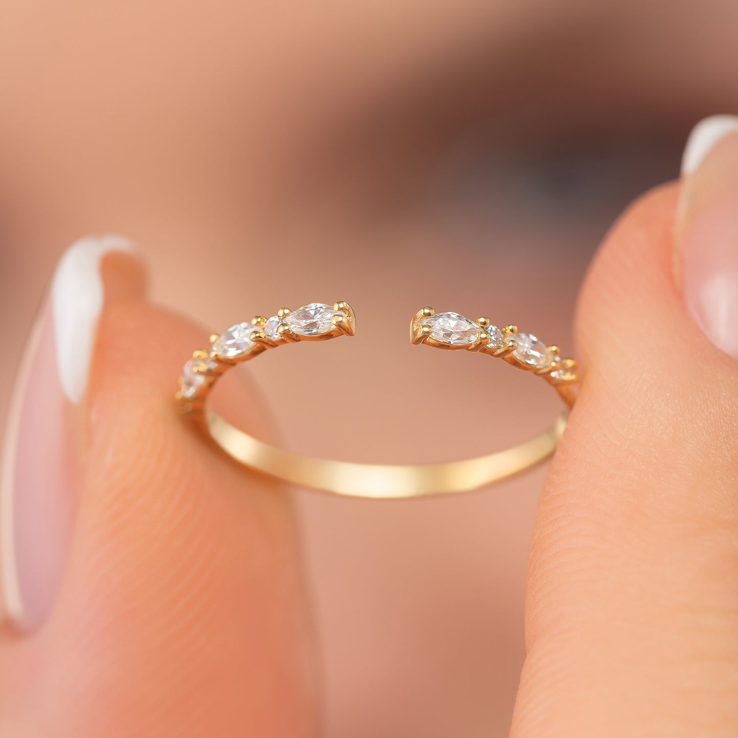 A close-up of a person's hand holding a gold ring with a row of small diamonds on the band.