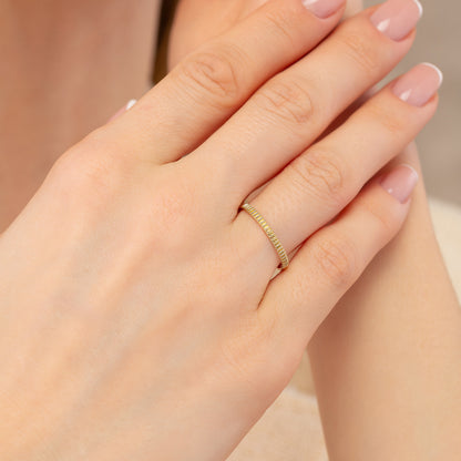 A close-up image of a person's hand wearing a gold ring on the ring finger.
