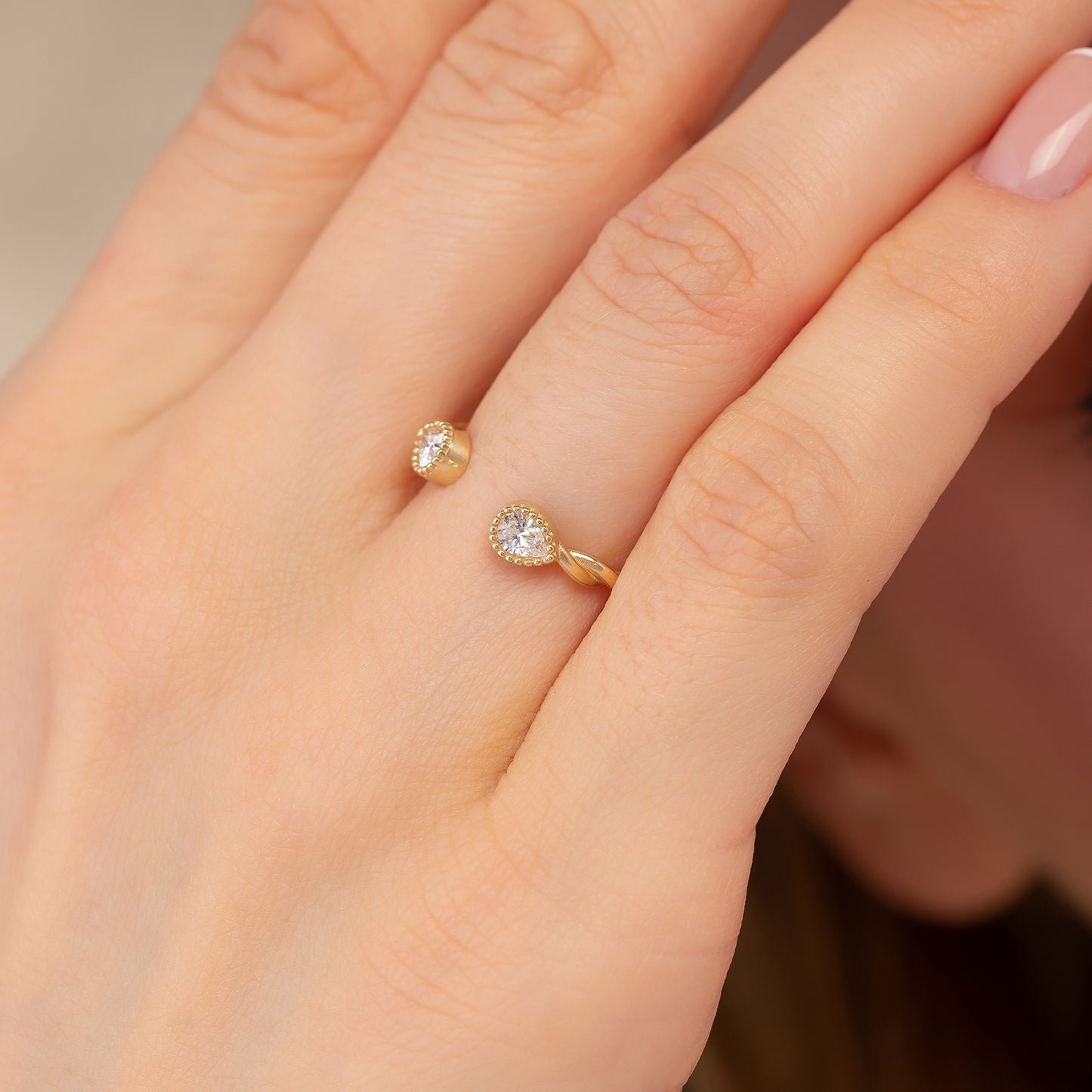 A close-up of a person's hand wearing a gold ring with two small diamonds.