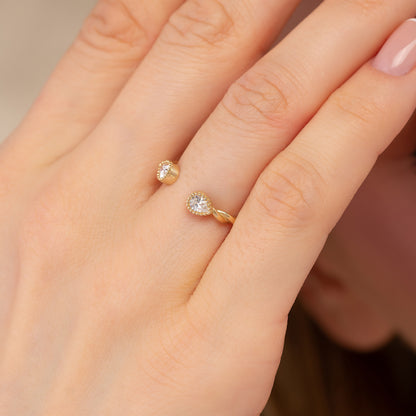 A close-up of a person's hand wearing a gold ring with two small diamonds.