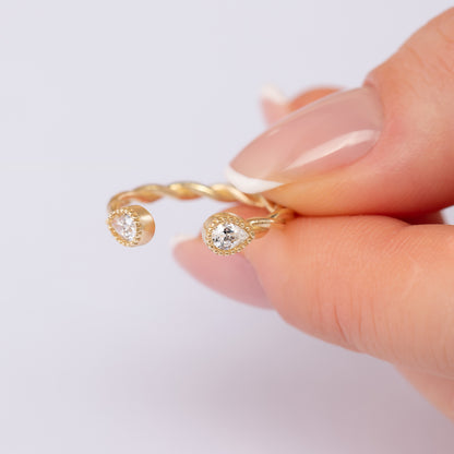 A close-up image of a person's hand holding a gold ring with two diamond-encrusted stones.