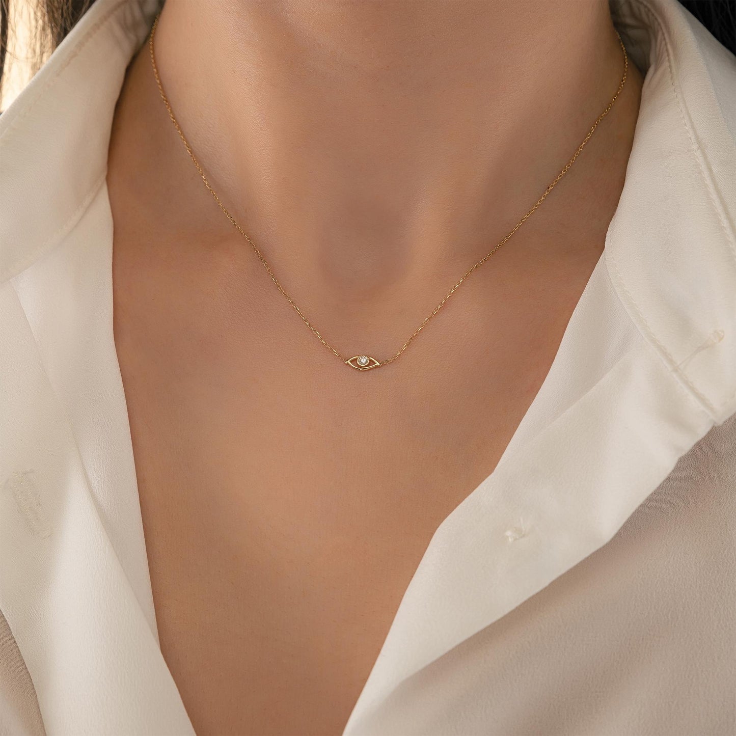 A close-up view of a person wearing a delicate gold necklace with a small pendant.
