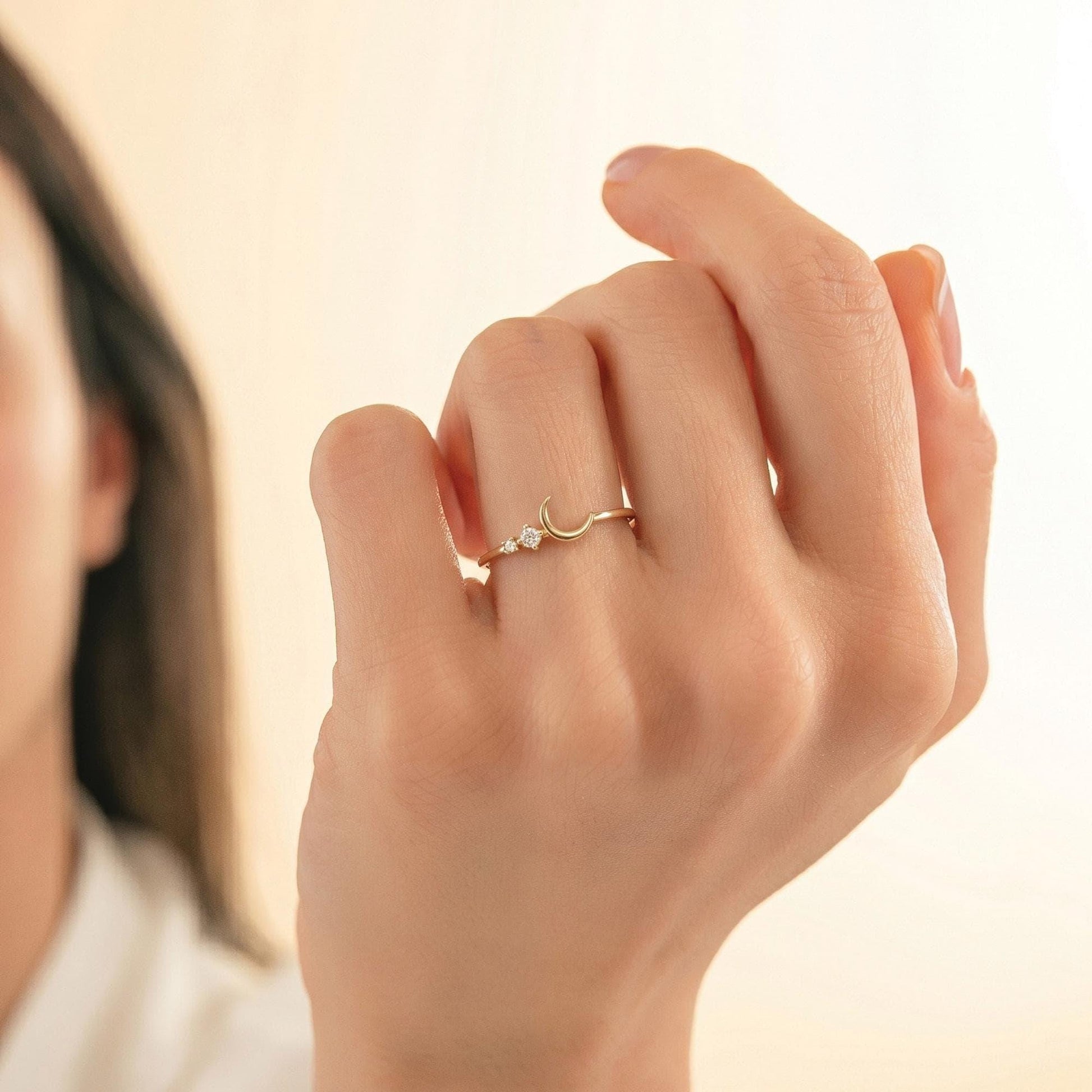 A close-up of a person's hand wearing a gold ring with a moon and star design.