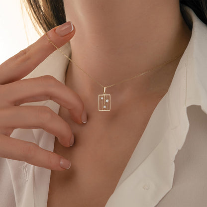 A close-up of a person's neck and chest wearing a gold necklace with a small pendant.