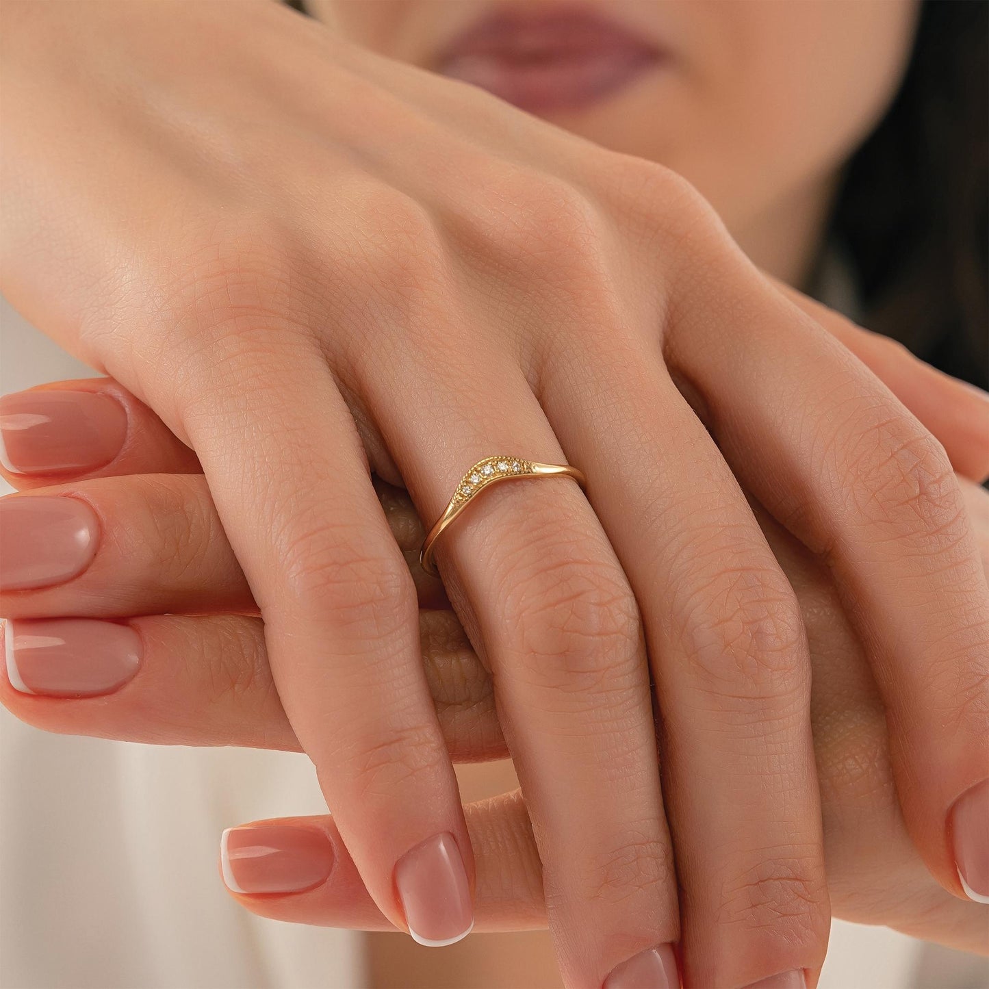 A close-up image of a person's hand wearing a gold ring with a diamond-like stone.