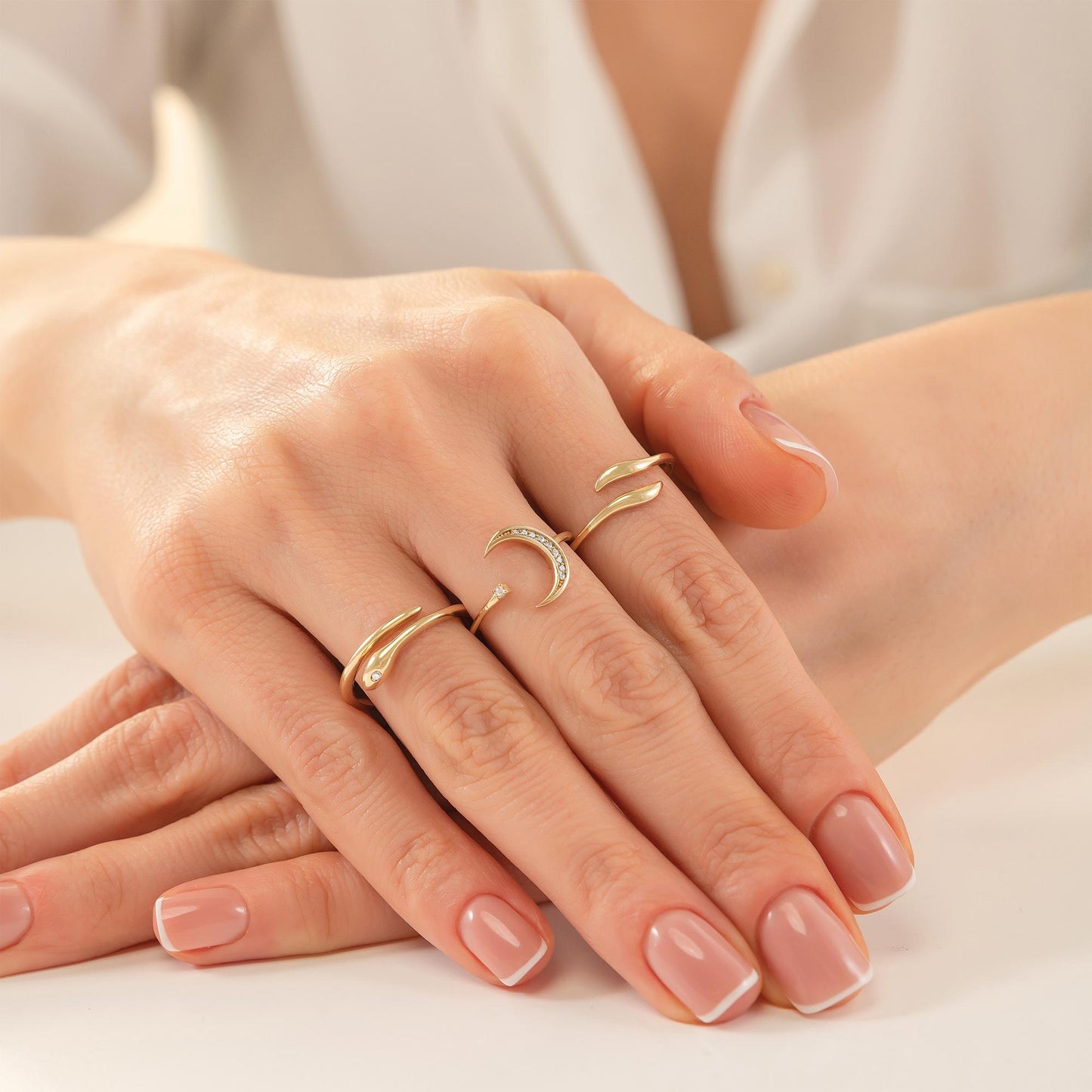 A close-up image of a person's hands wearing multiple rings on their fingers.
