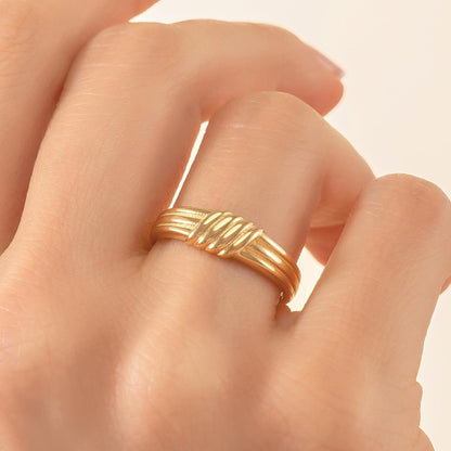 A close-up of a person's hand wearing a gold ring on the ring finger.