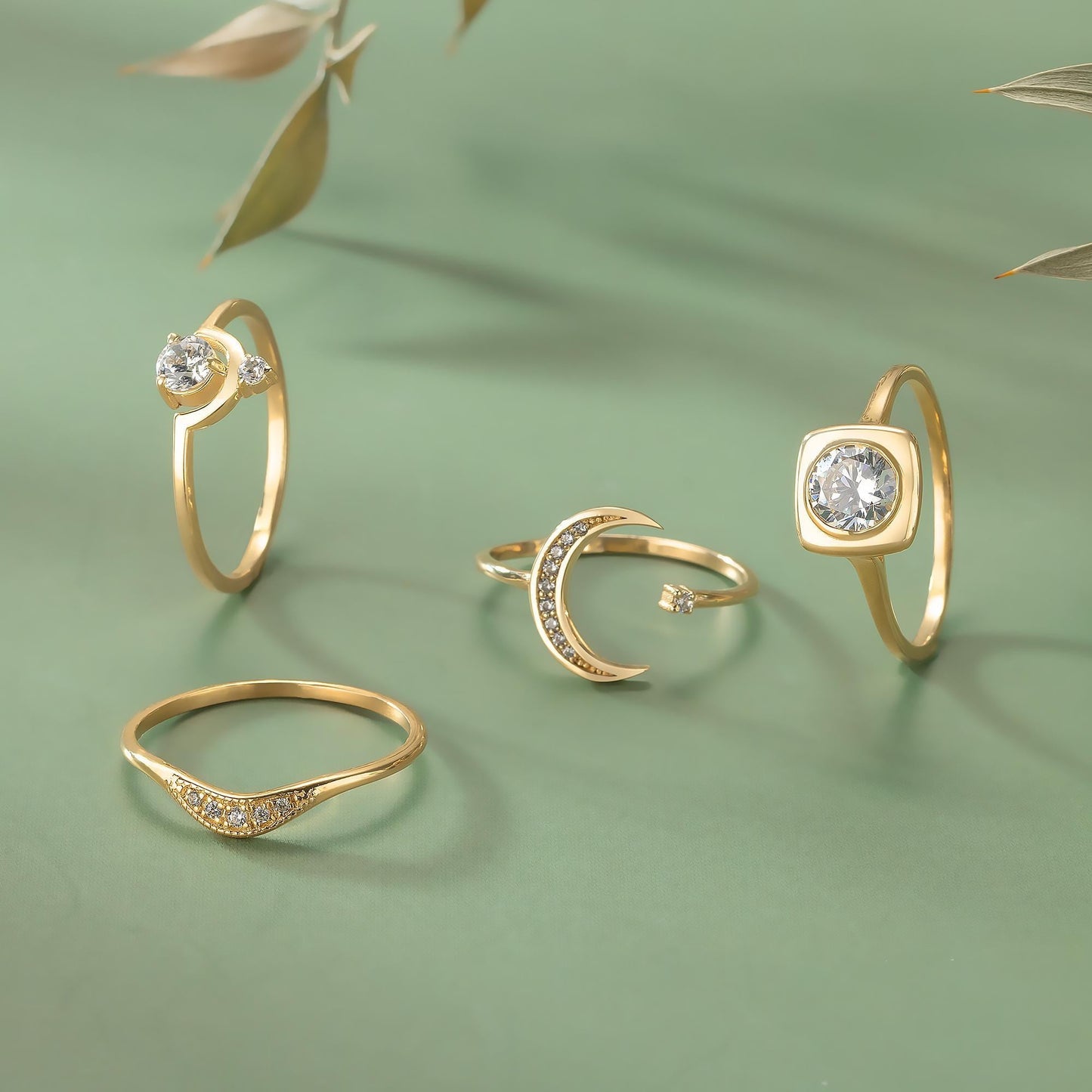 a collection of four gold rings with various designs, including a crescent moon and a square cut gemstone.