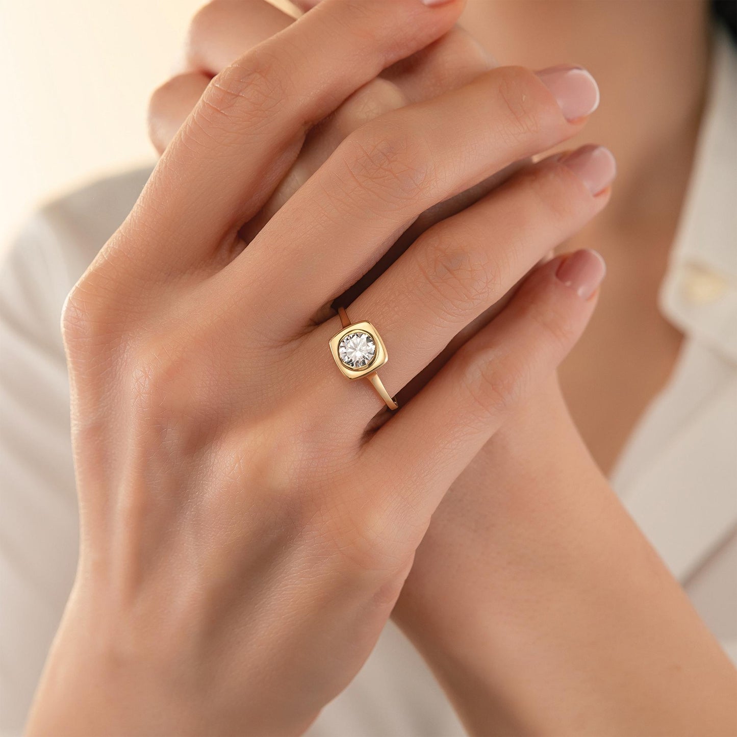 A close-up of a person's hand wearing a gold ring with a large diamond in the center.