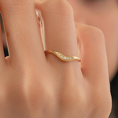A close-up of a person's hand wearing a gold ring with a small diamond accent.