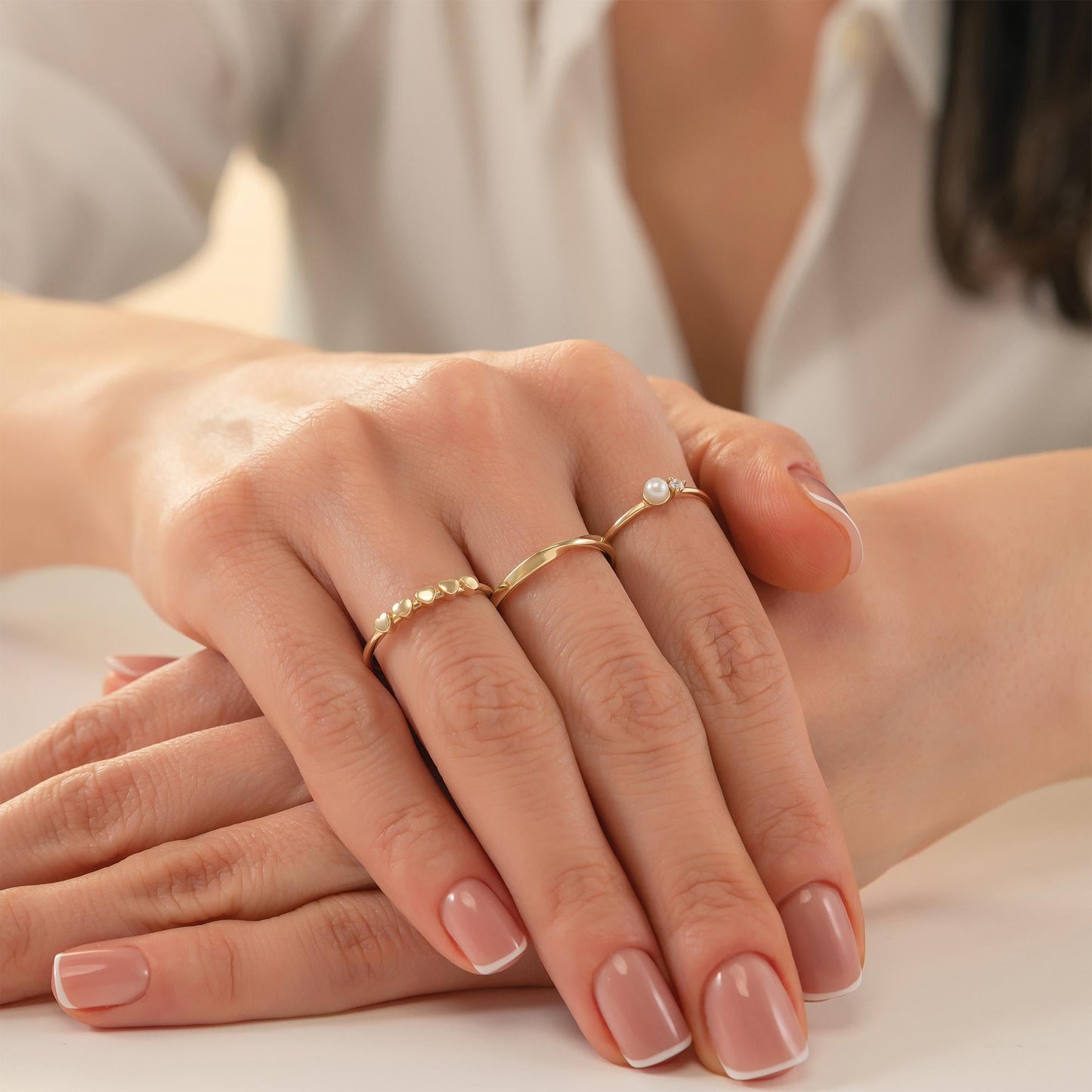 A close-up image of a person's hands wearing three rings on their fingers.