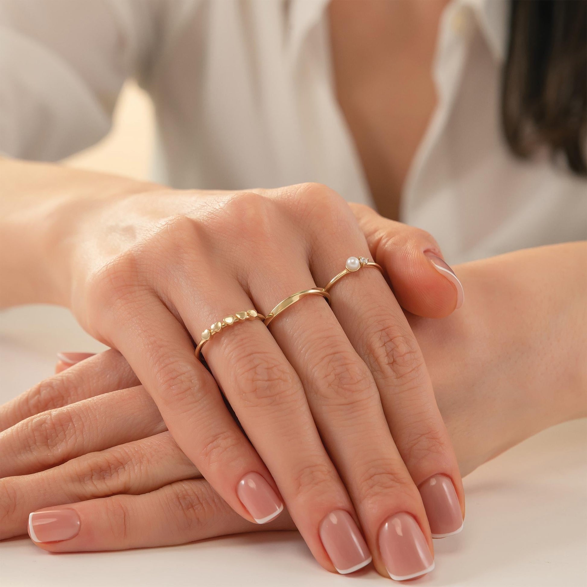 A close-up image of a person's hands wearing three rings on their fingers.