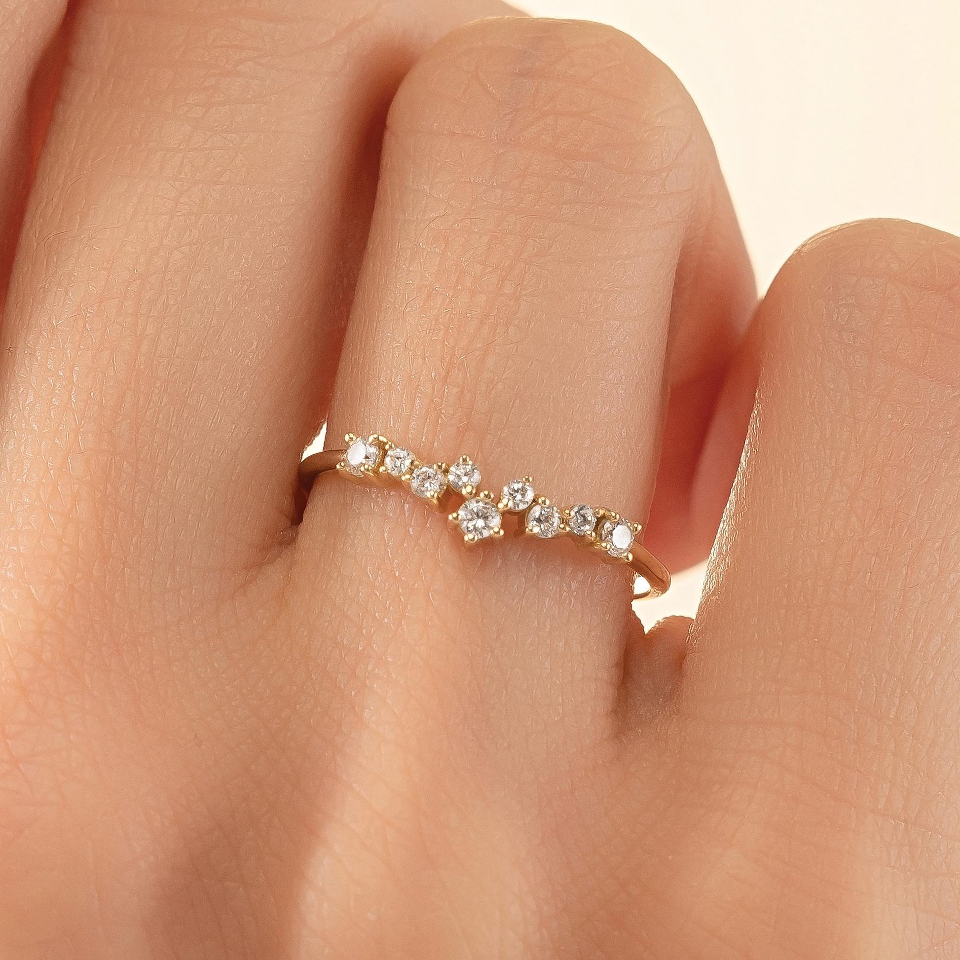 A close-up of a person's hand wearing a gold ring with a row of small diamonds on the ring band.