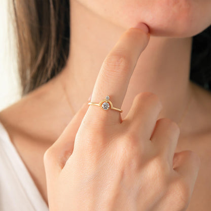 A close-up of a person's hand wearing a gold ring with a diamond, with their finger gently touching their lips.