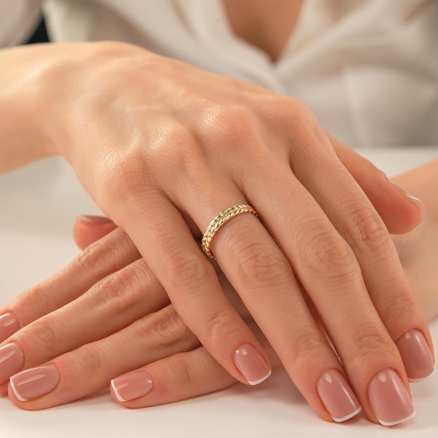 A close-up image of a person's hands with a gold ring on the ring finger.