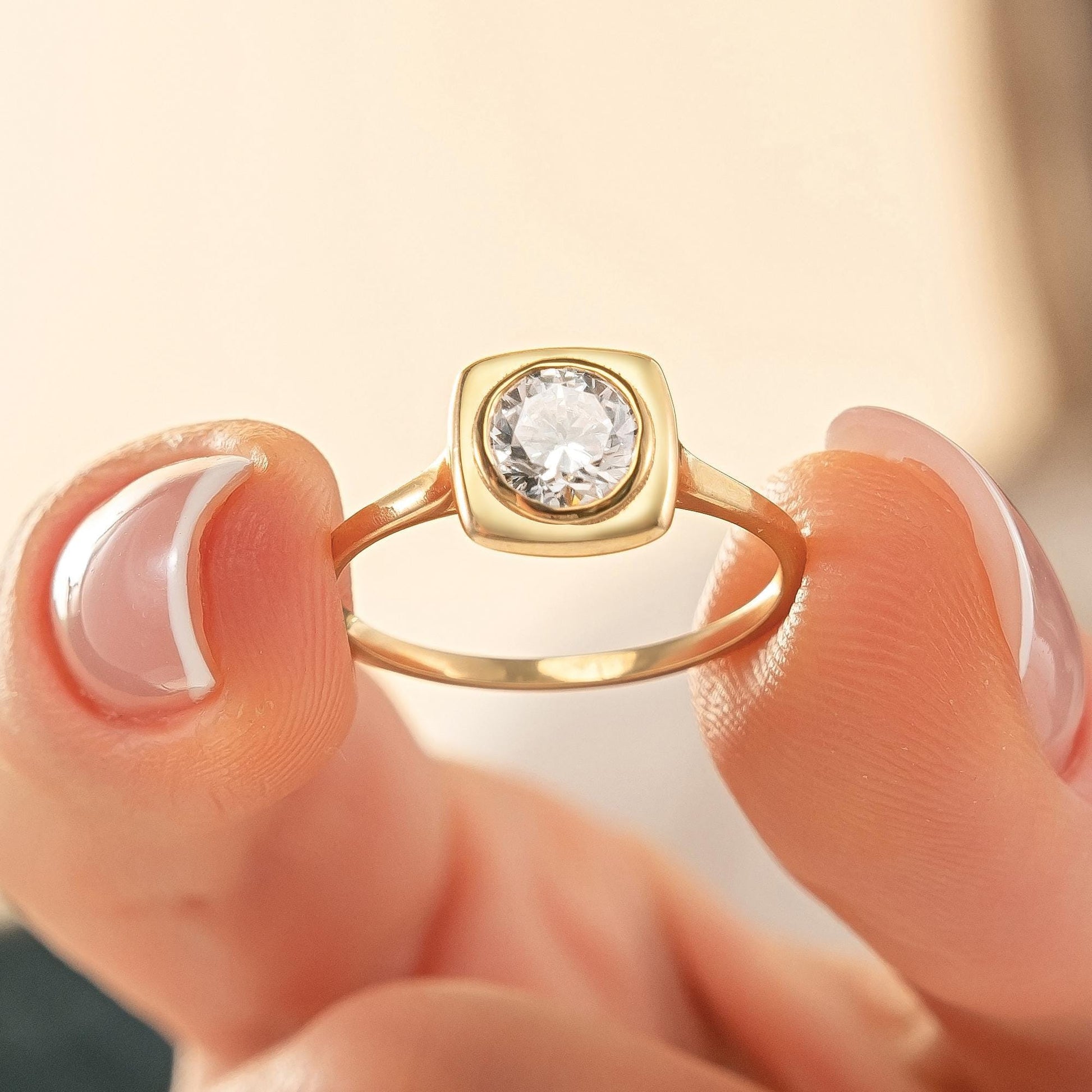 A close-up image of a person's hand holding a gold ring with a large diamond in the center.