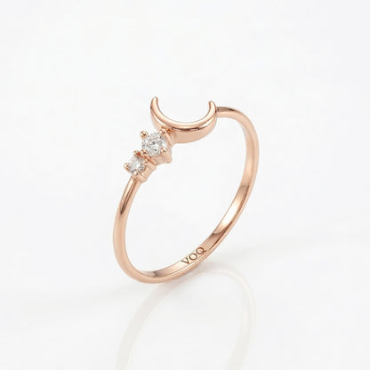 A rose gold ring with a crescent moon and three small diamonds set in the center.