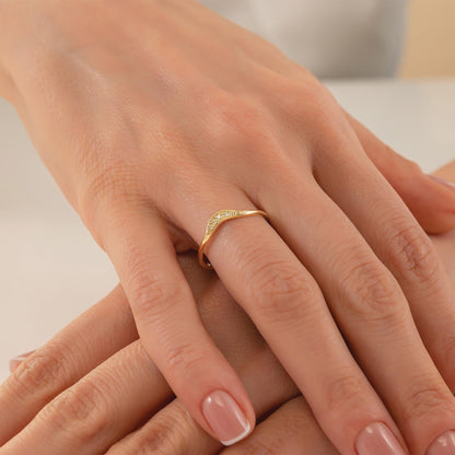 A close-up image of a person's hand wearing a gold ring with a diamond accent.