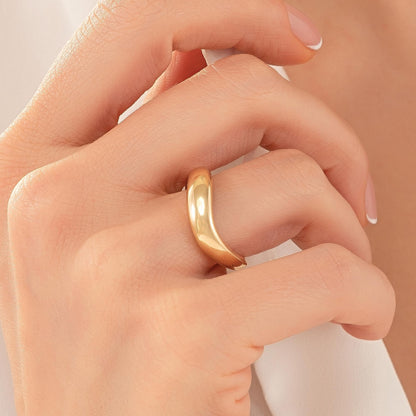 A close-up of a person's hand wearing a gold ring.