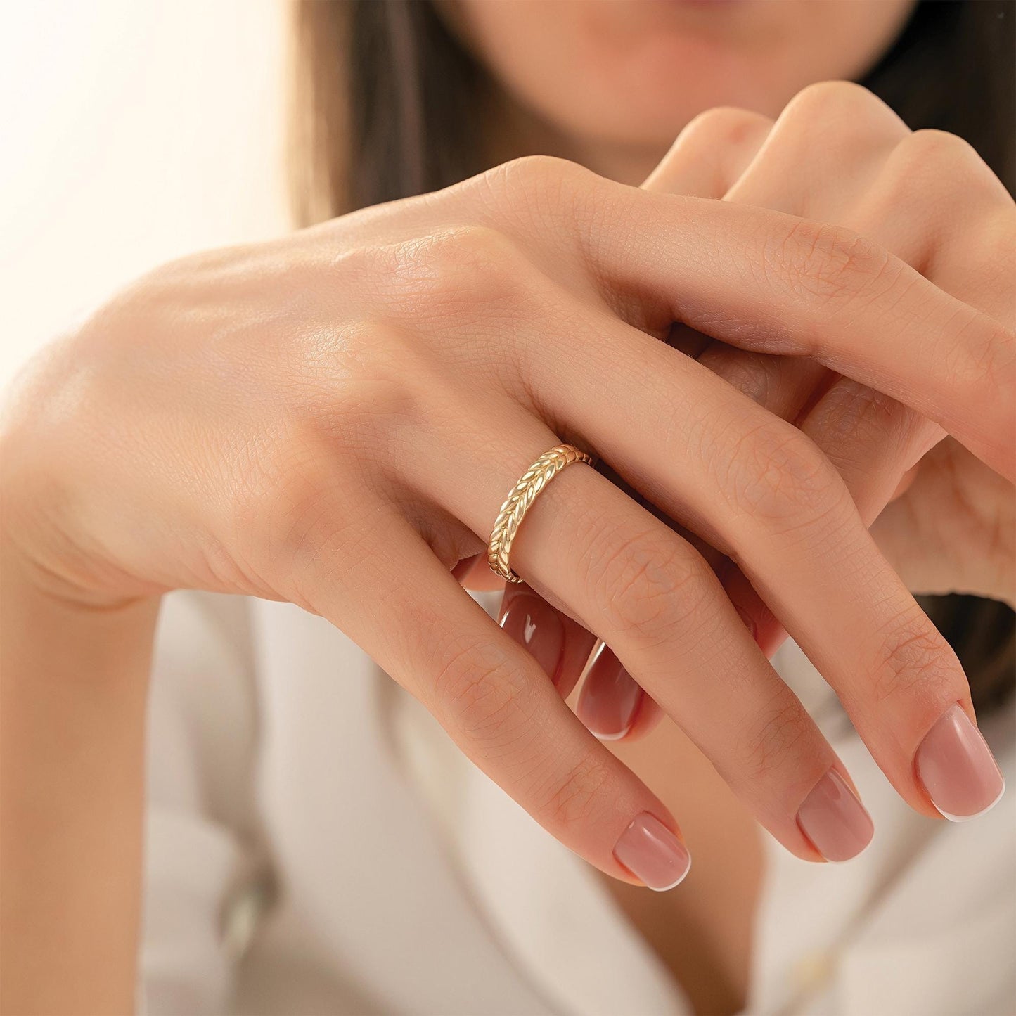 A close-up of a person's hand wearing a gold ring, with their fingers gently curled together.