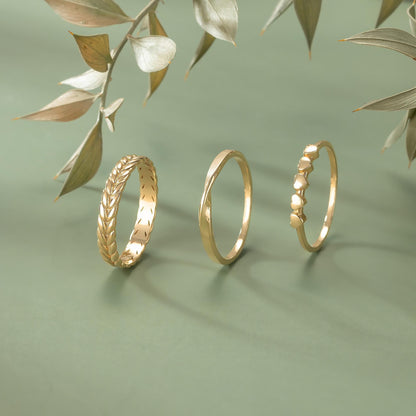 Three gold rings are displayed on a green background, with one ring on the left, one in the middle, and one on the right.