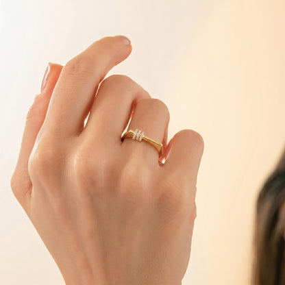 A close-up of a person's hand wearing a gold ring with a small diamond.