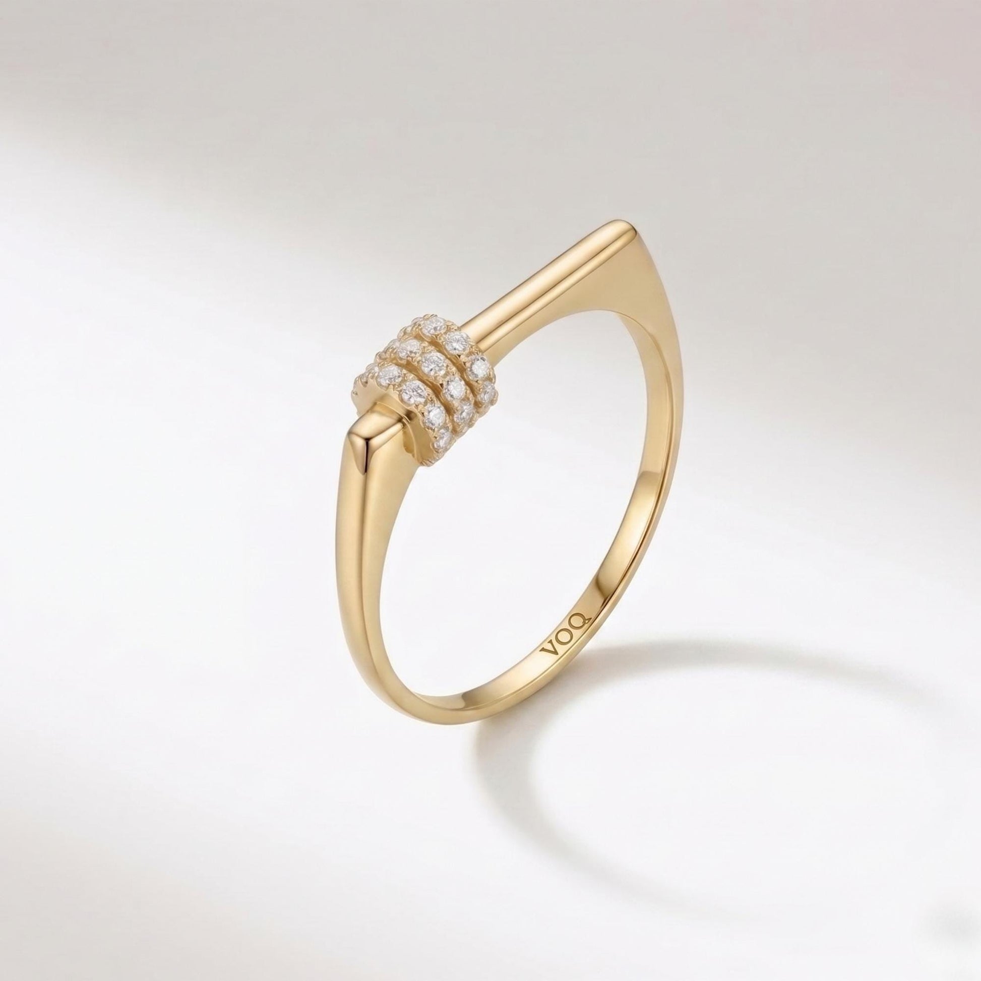 A gold ring with a diamond-encrusted band and a unique, angular design.