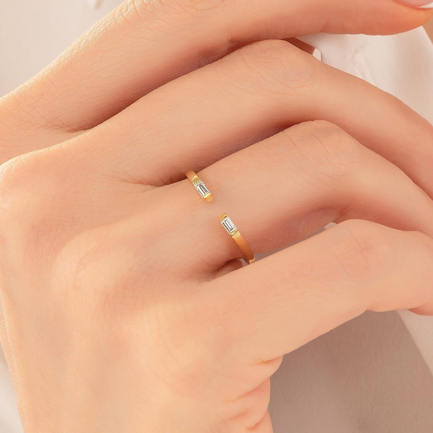 A close-up of a person's hand wearing a gold ring with a diamond-like stone.