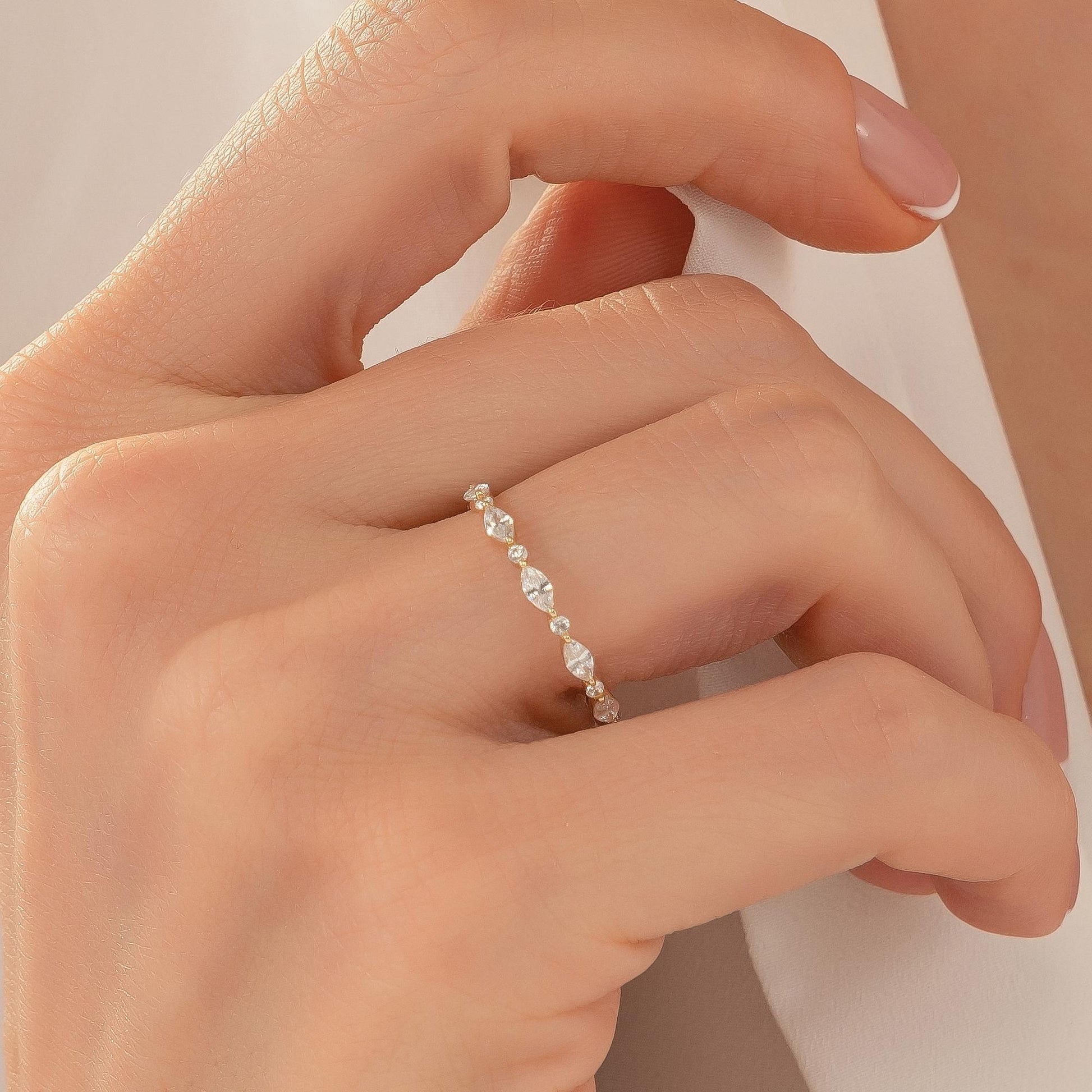 A close-up of a person's hand wearing a delicate gold ring with a row of small diamonds.