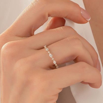 A close-up of a person's hand wearing a delicate gold ring with a row of small diamonds.