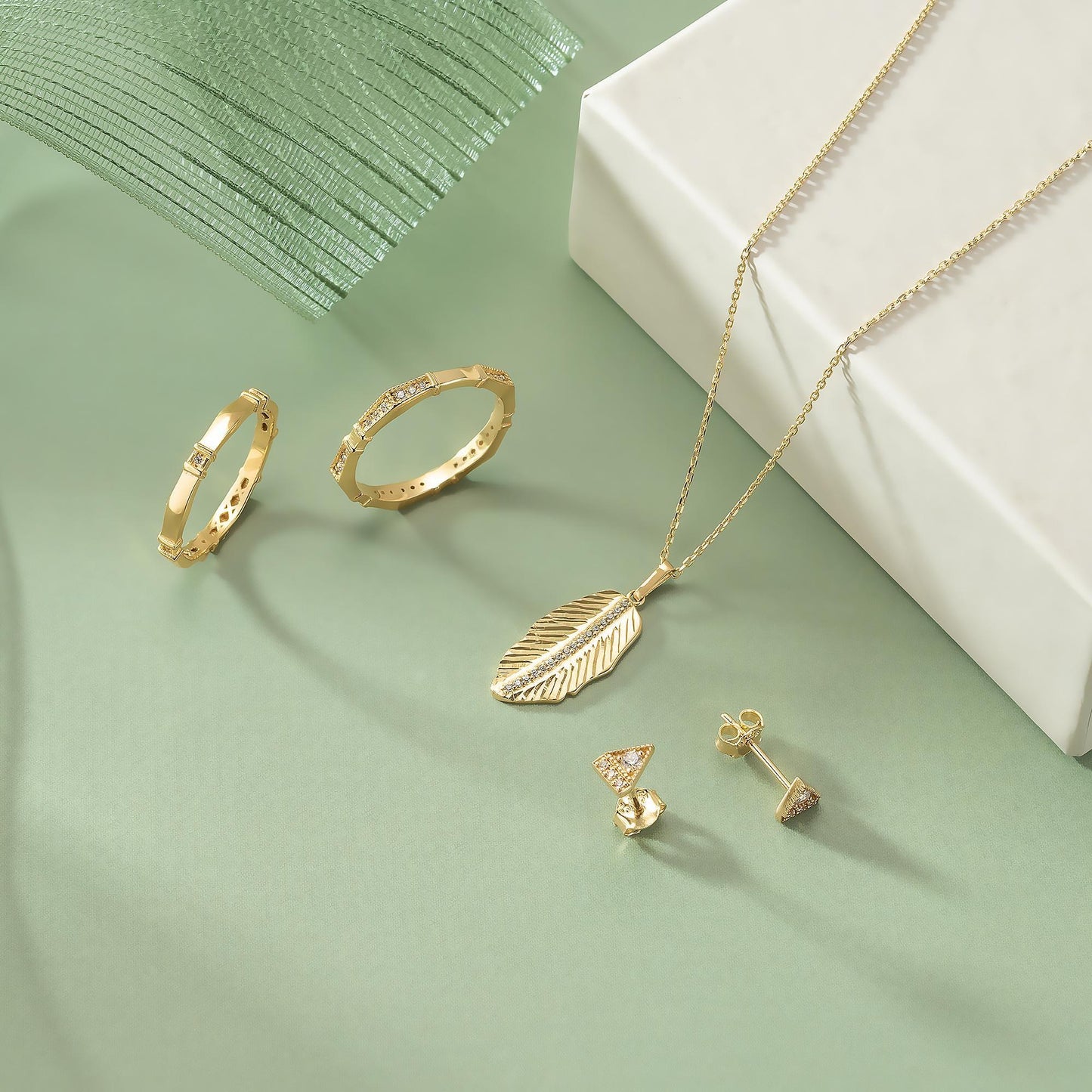 a collection of gold jewelry, including rings, earrings, and a necklace, arranged on a green background.