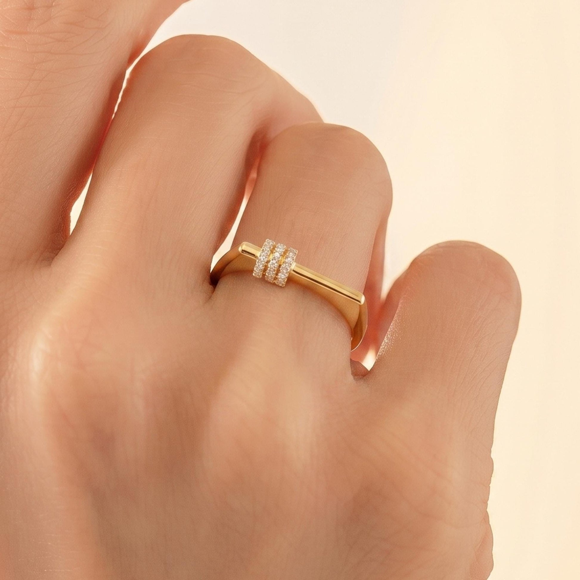 A close-up view of a person's hand wearing a gold ring with a small diamond accent.
