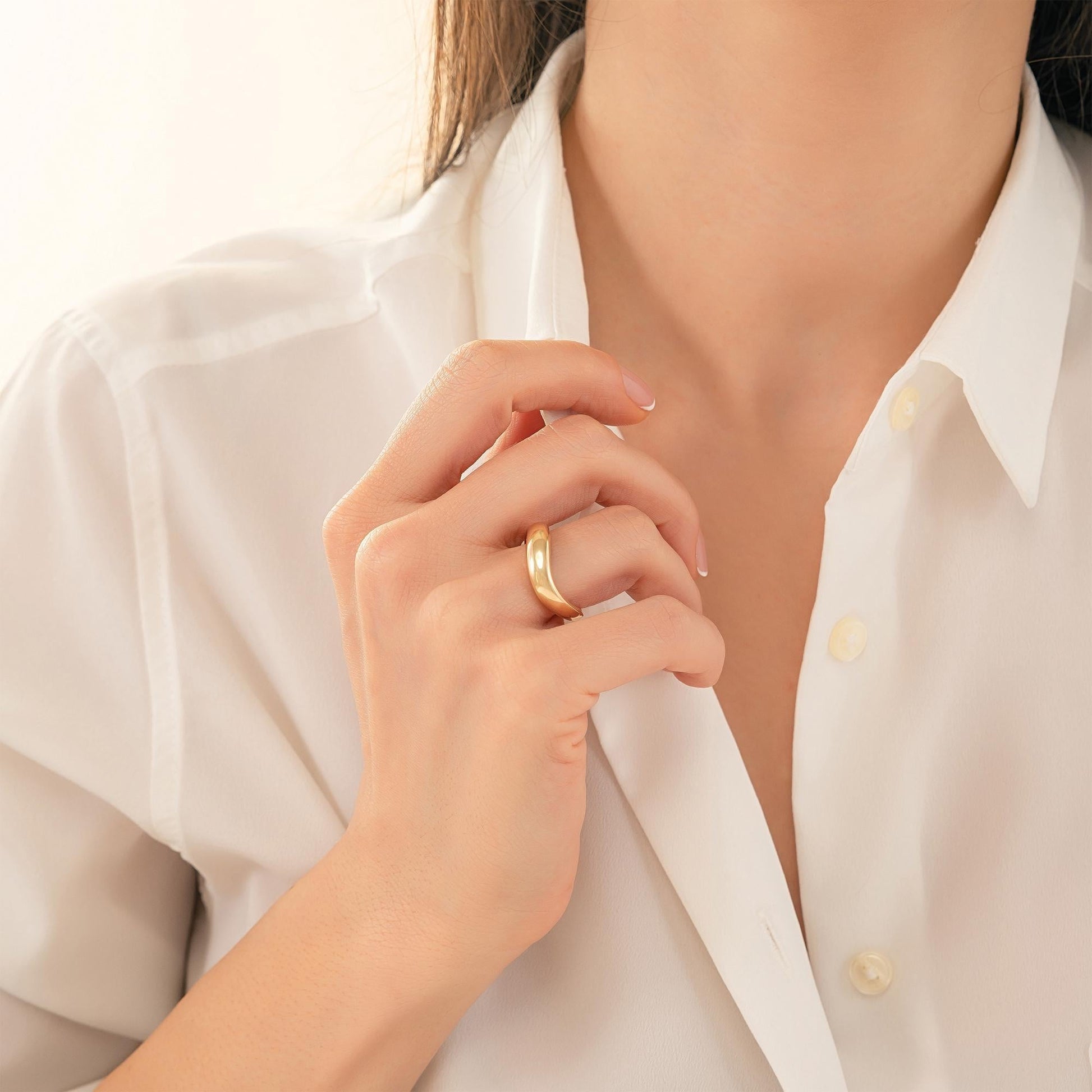 A close-up of a person's hand wearing a gold ring, with their fingers gently curled around the ring.