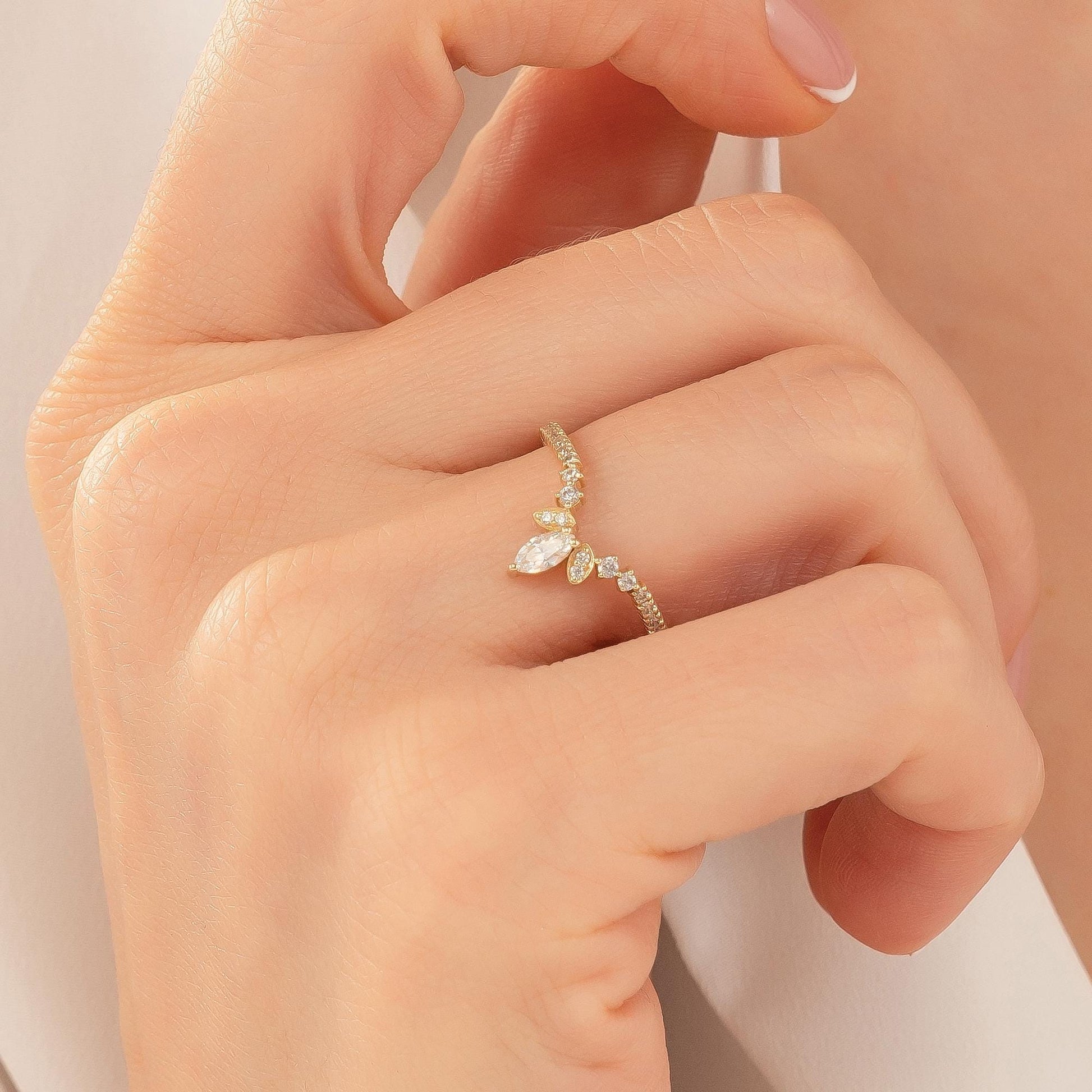A close-up of a person's hand wearing a gold ring with a diamond center stone.