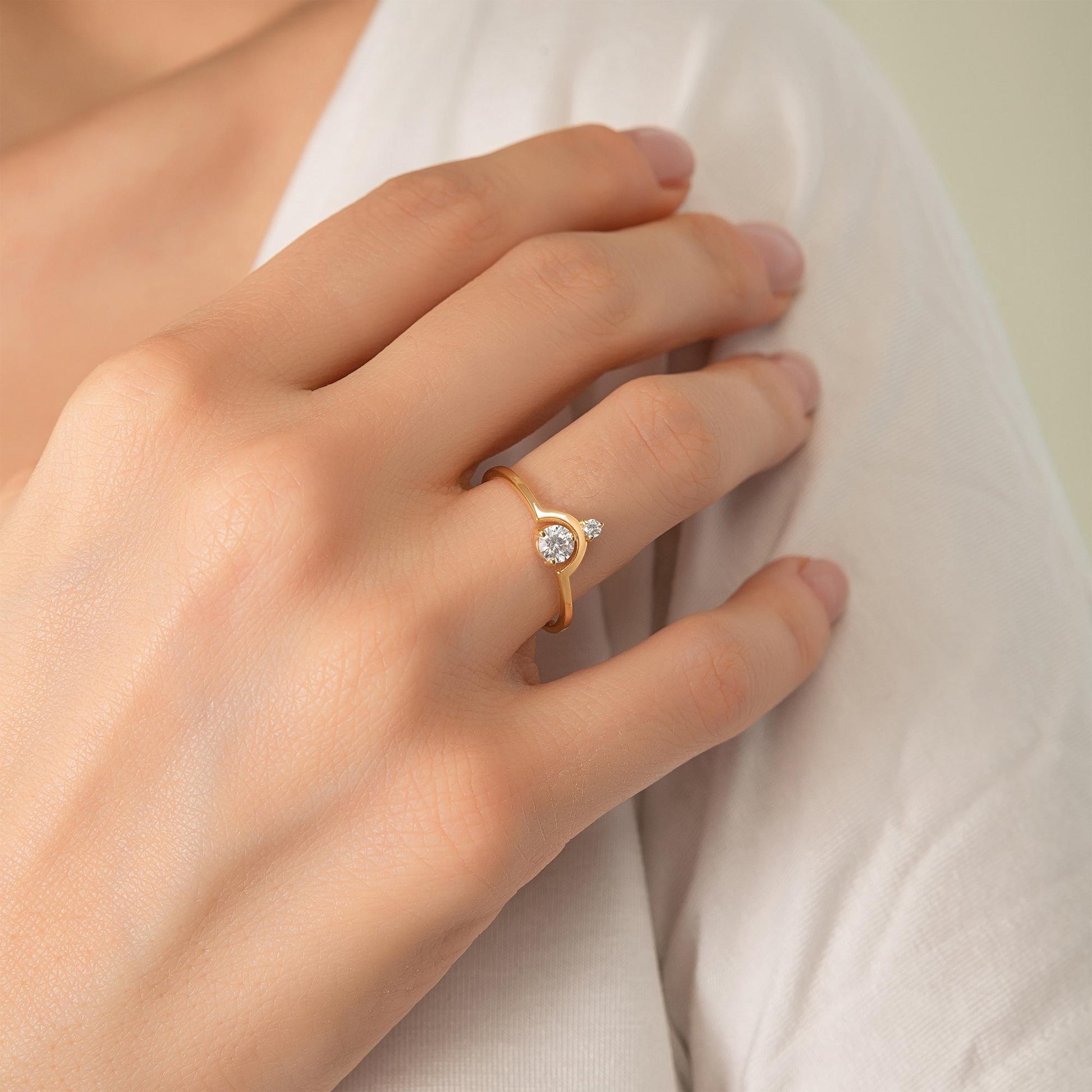 A close-up of a person's hand wearing a gold ring with a diamond.